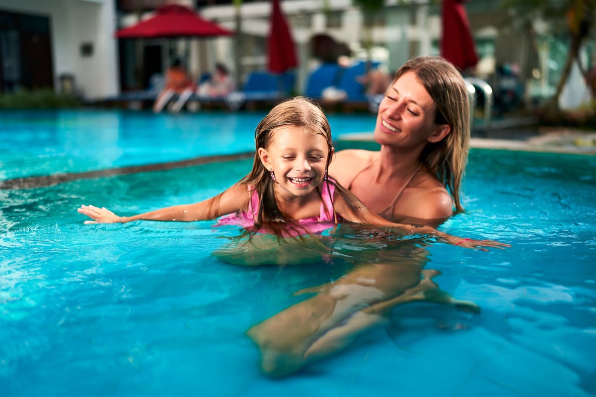 Mother teaching daughter to swim at luxury resort