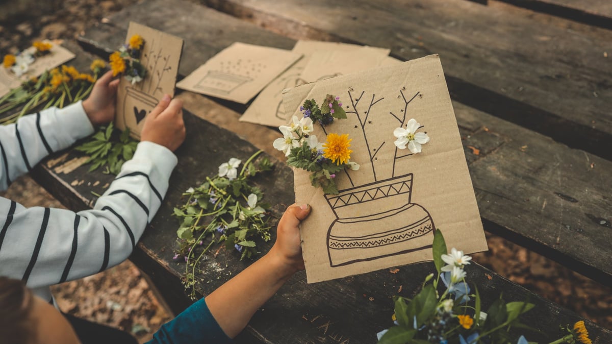 Children creating flower crafts at outdoor table
