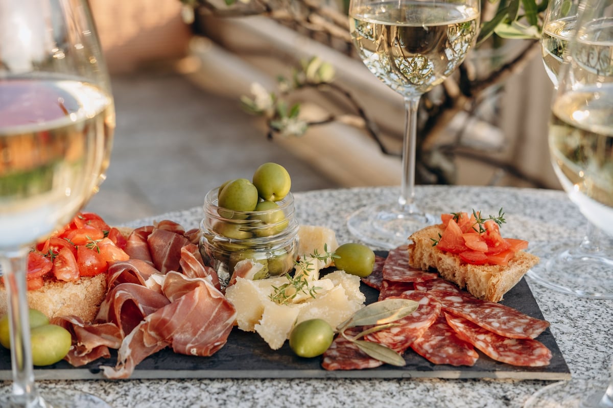 Wine glasses and a gourmet charcuterie board on a stone table