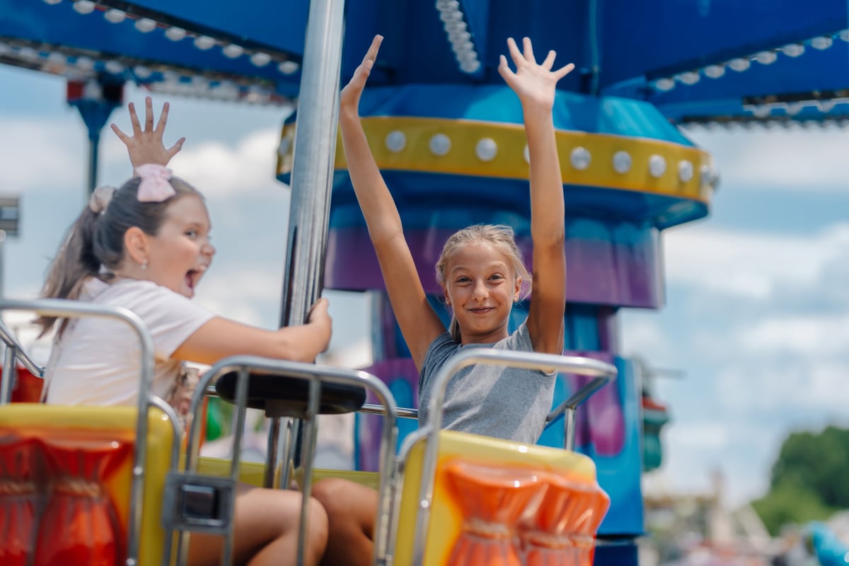 Two young girls enjoying a swing ride at an amusement park