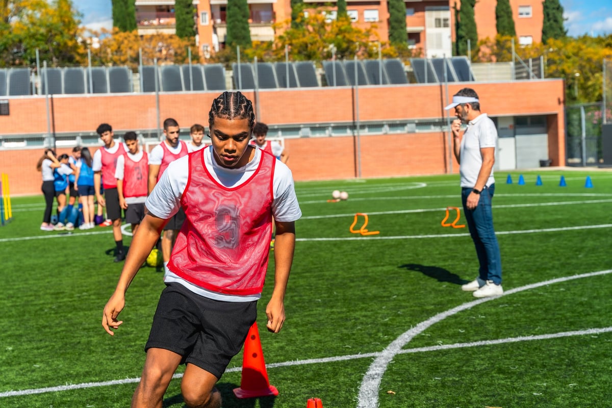 Young male athletes training soccer drills on artificial turf