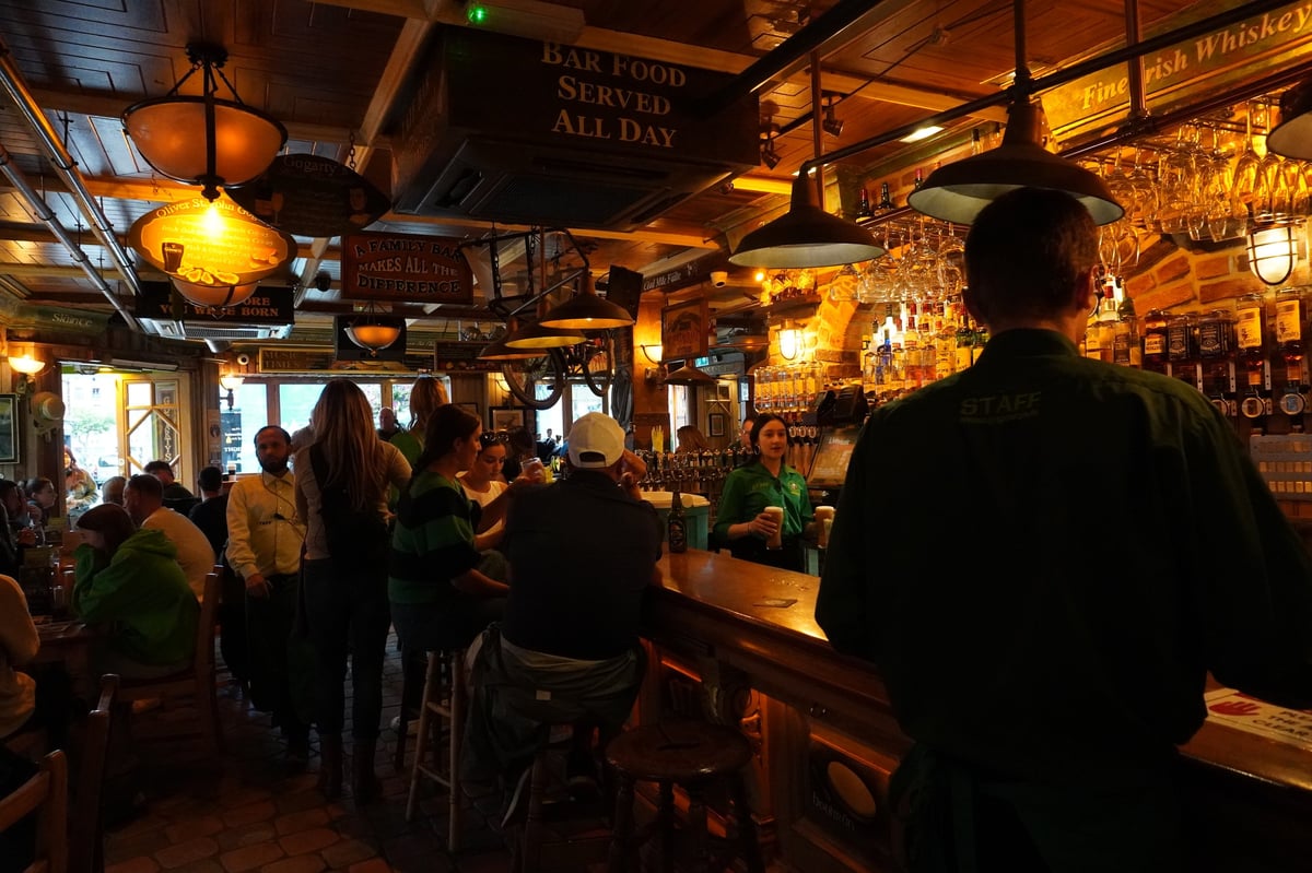 Interior view of a busy traditional Irish pub showing customers at the bar under warm atmospheric lighting