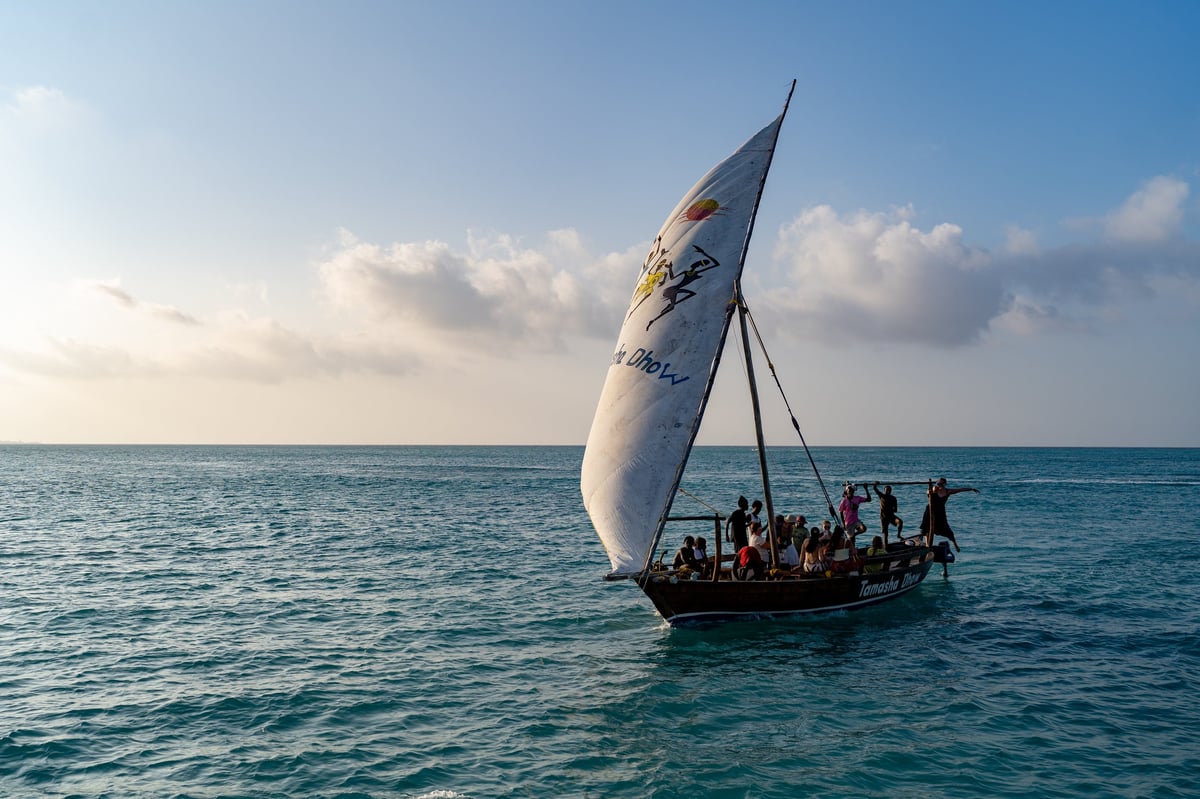 Traditional wooden dhow boats with passengers sailing along the coast of Zanzibar, Tanzania, on January 2, 2026.