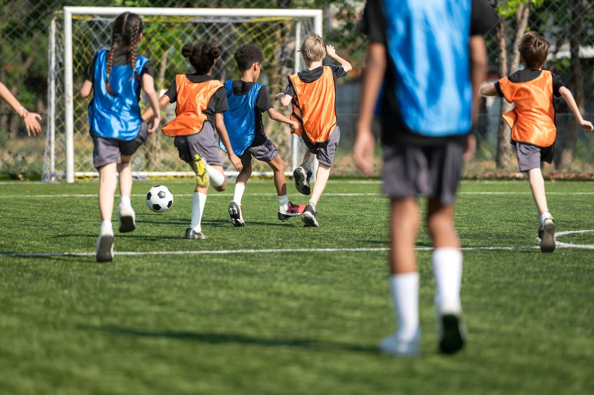 Group of international school kids playing soccer together on the field