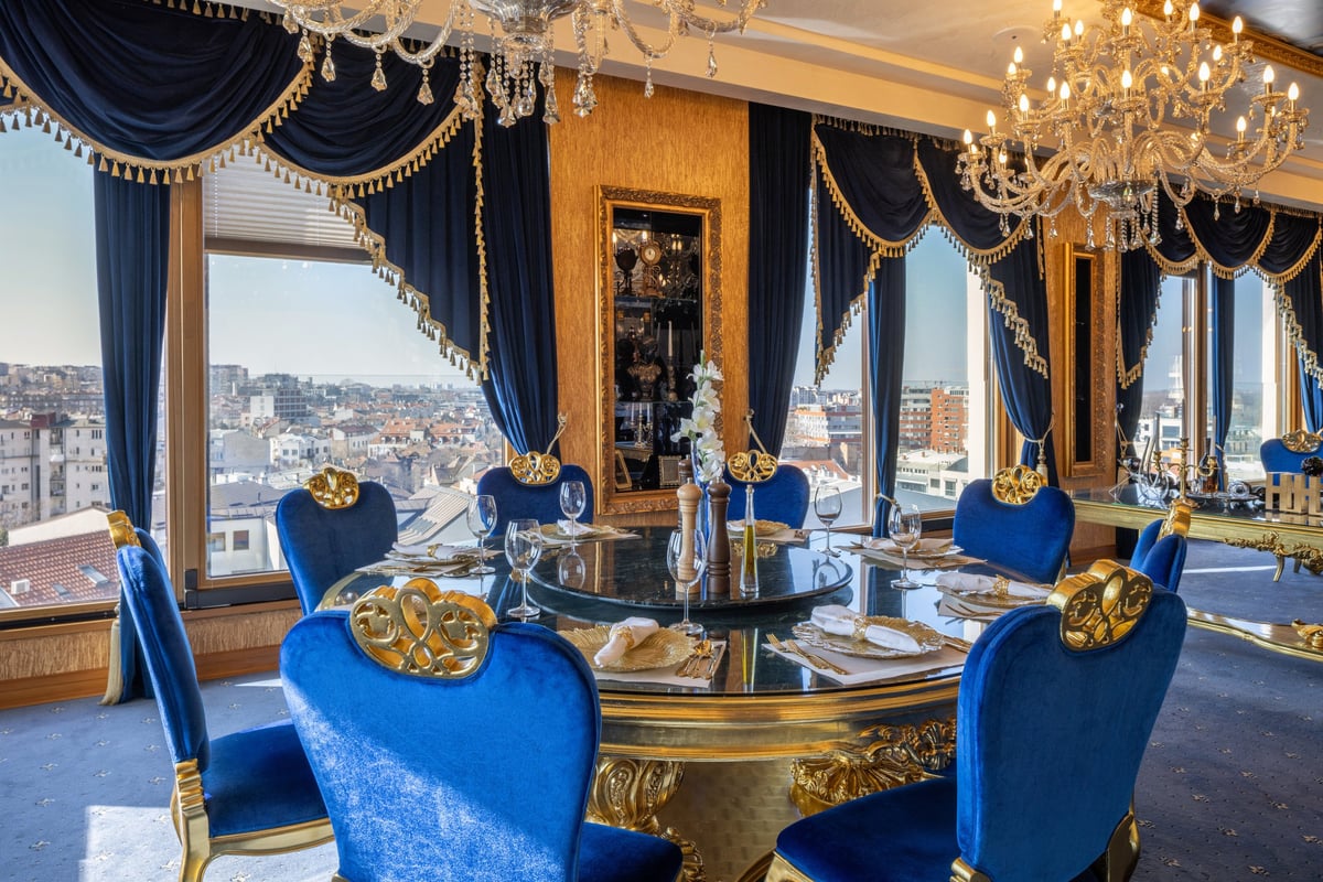 Luxurious dining room interior with royal blue chairs, golden decor and panoramic city view