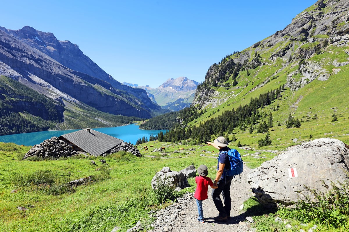 Hikers beside a clear alpine lake in the Swiss Alps in summer.