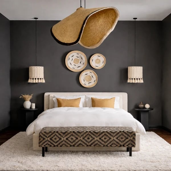 Modern bedroom with white upholstered bed, woven wall art, pendant lights, and gold accents against dark gray walls