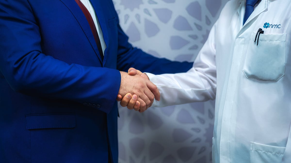Businessman in blue suit shaking hands with healthcare professional in white coat
