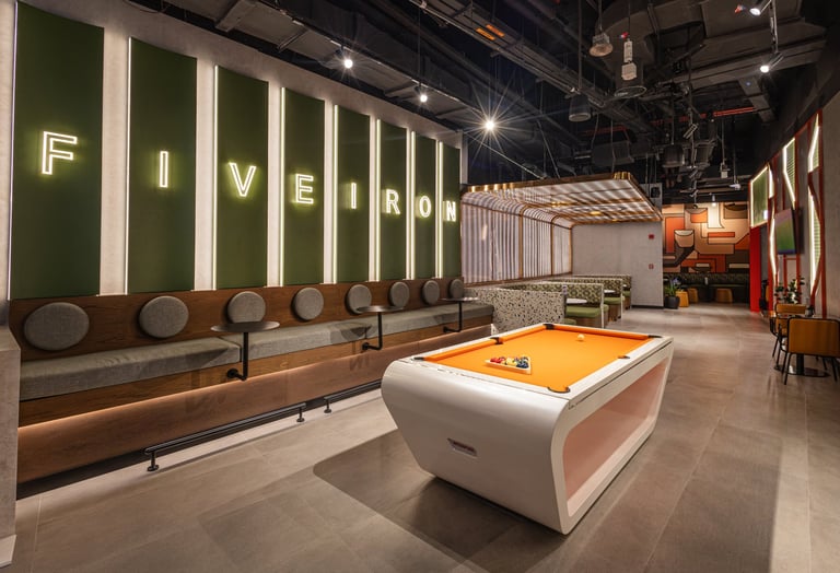 Modern game lounge with illuminated wall signs spelling Five Frog, pool table, and seating along the wall