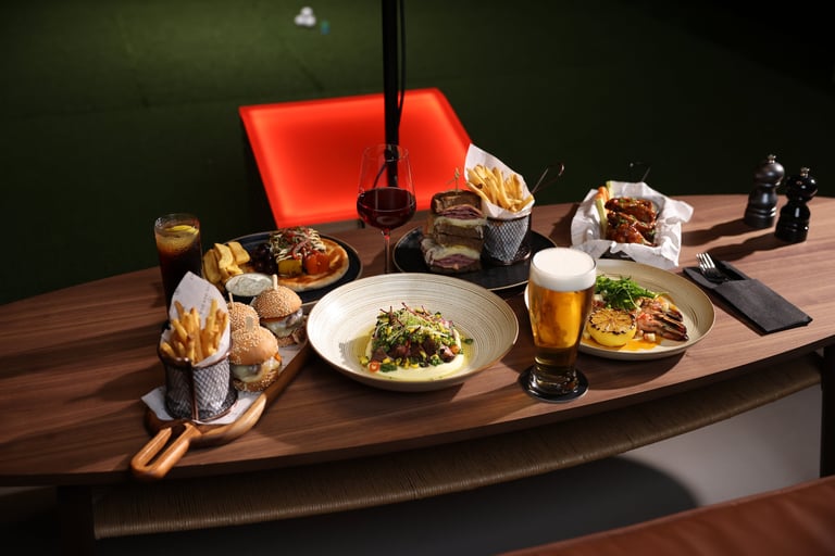 Upscale restaurant table with plated dishes, appetizers, beer, and red decor against a dark green wall