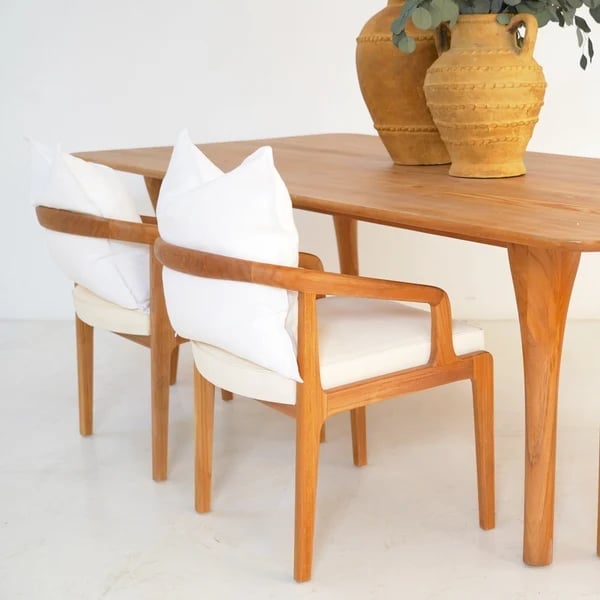 Wooden dining table with upholstered chair and decorative terracotta vase with greenery