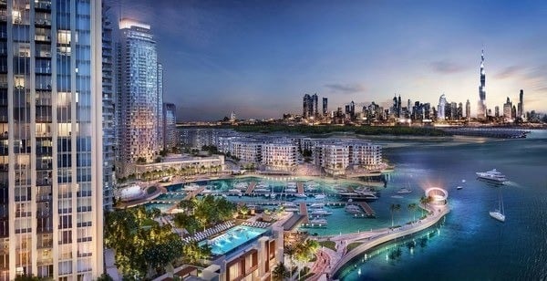 Waterfront development with luxury residential towers, pools, and beachfront overlooking a city skyline and blue water