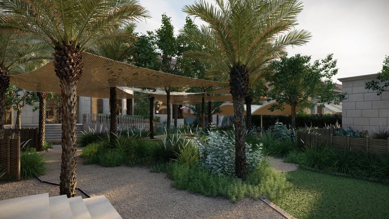 Modern outdoor pavilion with wooden pergola, palm trees, and landscaping. People gathered in shaded seating area with desert plants and gravel pathways.