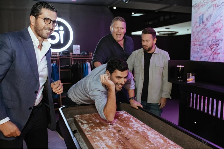 Man leaning over interactive display with four men in business casual attire observing in modern tech environment