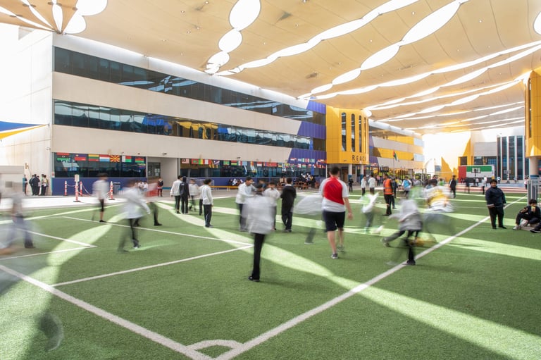 Indoor soccer facility with multiple artificial turf fields, overhead lighting, and people playing and watching games