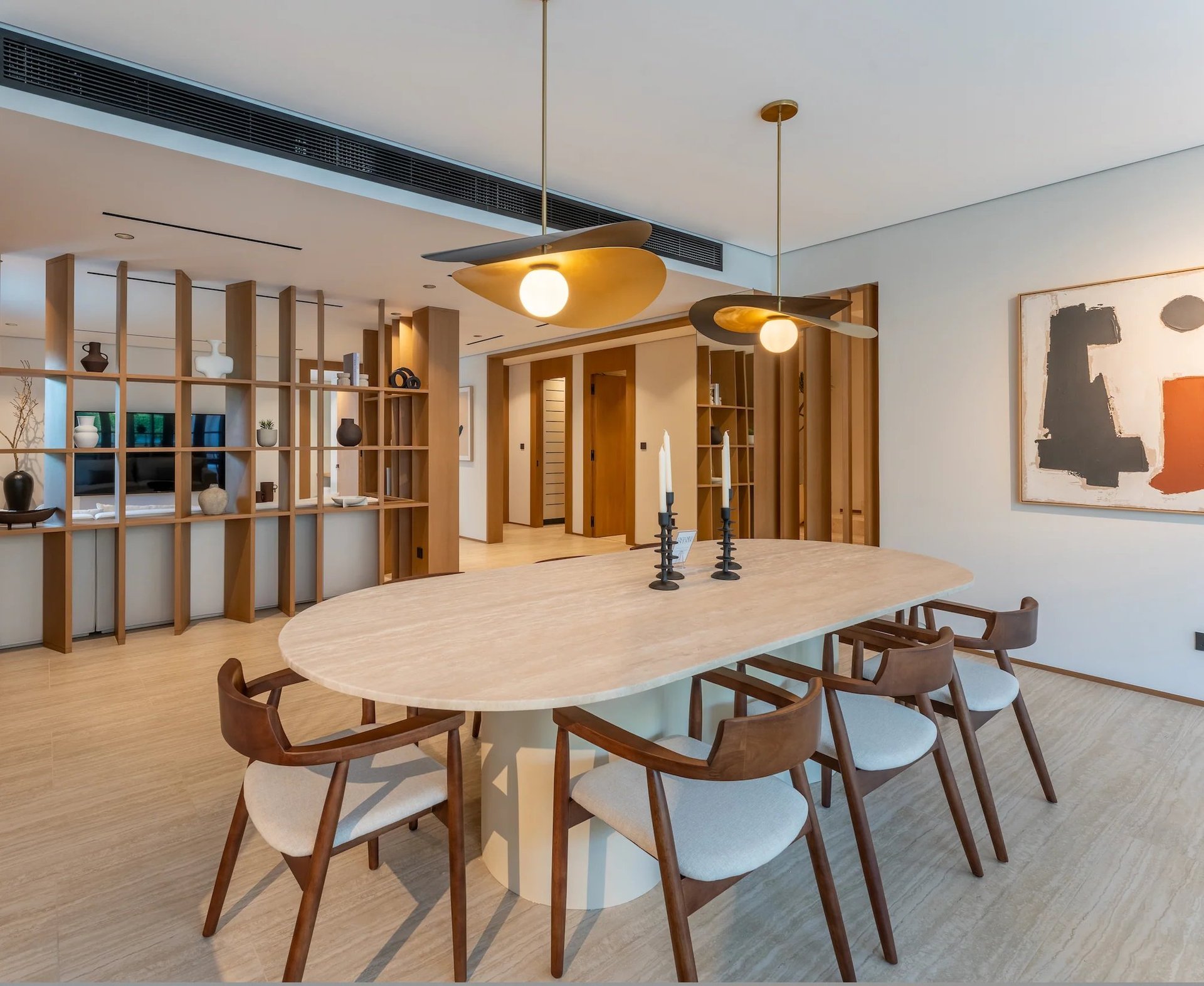 Modern dining room with wooden table, mid-century chairs, pendant lights, and minimalist decor with shelving units